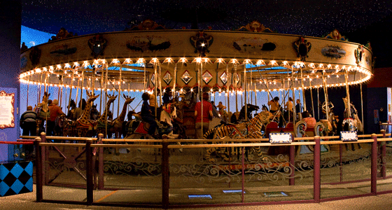 Ornate carousel with people riding it.