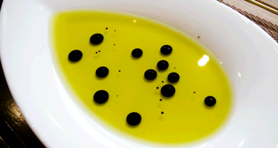 Olive oil with balsamic vinegar drops on a white plate.