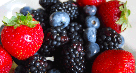 A close-up of strawberries, blueberries, and raspberries mixed together.