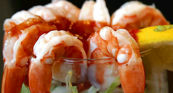 A glass of shrimp cocktail with a lemon wedge garnish.