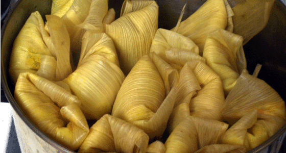 A pot of tamales being cooked in corn husks.
