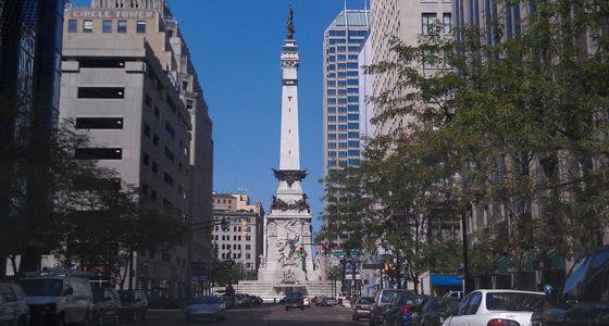 Soldiers and Sailors Monument with downtown buildings on either side from a distance.