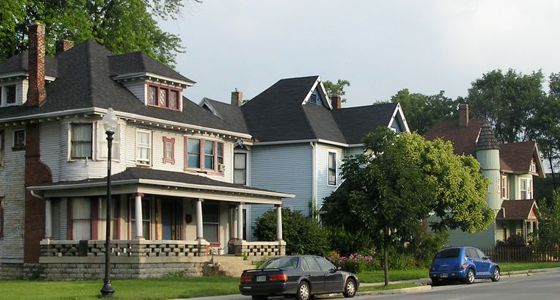A row of victorian style houses, surrounded by trees and bushes.  